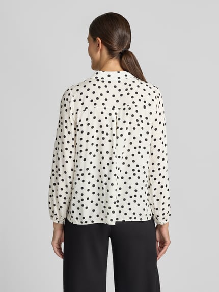 Vrouwenmodel draagt Relaxed Fit blouse uit zuiver viscosemix Model 'Valeria' van ZABAIONE, wit met zwarte stippen, blouse met lange mouwen, serafinohals, ruglengte bij maat S 54 cm, mouwlengte bij maat S 58 cm, rugaanzicht, dames blouse.
