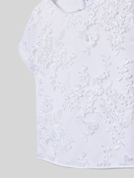 Meisje draagt Maxikleid mit Rundhalsausschnitt van DANAMADE, wit, bloemenstructuur, strikdetail, detailopname bovenlichaam.