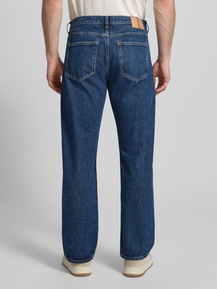 Männermodel trägt Jeans im Used-Look Modell 'Type 2' von Wood Wood in Blau, Relaxed Fit, reine Baumwolle, Ganzkörperansicht Rückansicht.