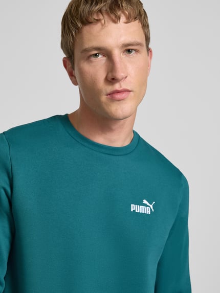 Männermodel trägt Regular Fit Sweatshirt mit Logo-Stitching von PUMA PERFORMANCE, mieszanka bawełny, okrągły dekolt, wyhaftowane logo, Nahaufnahme Oberkörper.