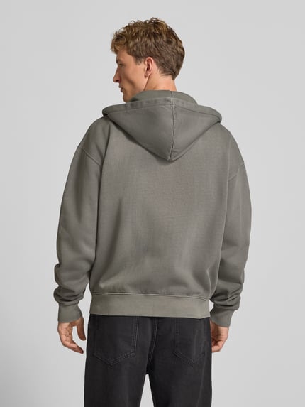 Männermodel trägt Regular Fit Sweatjacke aus Baumwoll-Mix von PEGADOR in Grau mit Kapuze und gerippten Abschlüssen, Ganzkörperansicht Rückansicht.