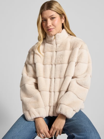 Vrouwenmodel draagt Regular Fit Jacke aus Kunstfell van PETITE M., lichtbeige met doorgestikte naden, opstaande kraag, ritssluiting, ruglengte maat 36: 57 cm, schouderbreedte: 42 cm, borstwijdte: 56 cm, mouwlengte: 57 cm, textuur imitatiebont, frontale half-tot-kniën aanzicht.