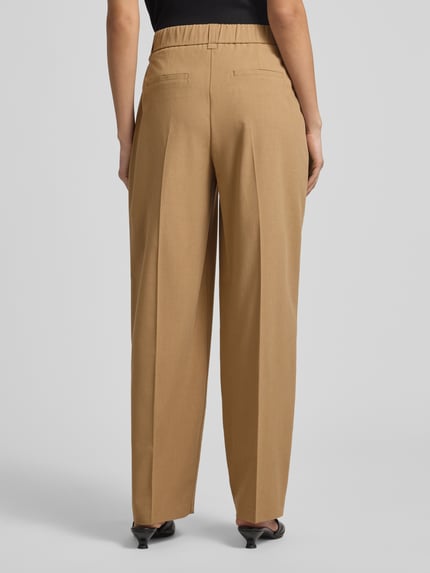 Frauenmodel trägt Barrel Fit Hose Modell 'Moira Bloom' von OPUS PANTS in Beige mit Bügelfalten, aus Baumwoll-Mix, Ganzkörperansicht Rückansicht.