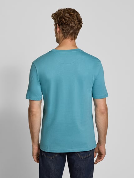 Męski model nosi Regular Fit T-Shirt aus reiner Baumwolle von Scotch & Soda w kolorze turkusowym, krój regular fit, wyhaftowane logo, okrągły dekolt, bawełna, długość tyłu w rozmiarze M: 61 cm, widok całej sylwetki z tyłu.