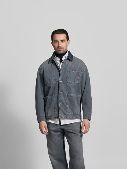 Männermodel trägt Regular Fit Hemdjacke in Denim-Optik von Diesel aus reiner Baumwolle, mit aufgesetzten Taschen und Knopfleiste, Ganzkörperansicht von vorne.