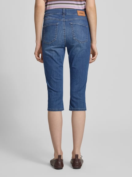 Vrouwenmodel draagt Caprijeans met steekzakken model 'Anacapri' van Angels, slim fit, katoenmix met stretch, blauwe kleur, geheel achteraanzicht.