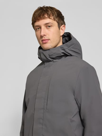 Męski model nosi kurtkę z kapturem, szary kolor, kurtka z zakrytym zamkiem błyskawicznym, regular fit, JACK & JONES, Model 'KEEN', Patki przy mankietach, długość tyłu w rozmiarze M: 72 cm, szerokość ramion w rozmiarze M: 49 cm, szerokość klatki piersiowej w rozmiarze M: 60 cm, długość rękawów w rozmiarze M: 68 cm, zdjęcie: zbliżenie na górną część ciała.