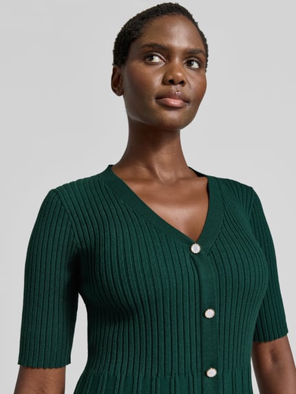 Frauenmodel trägt Strickkleid in Minilänge mit Viskose-Anteil von Christian Berg Woman in Dunkelgrün, Ripp-Optik, Nahaufnahme Oberkörper.