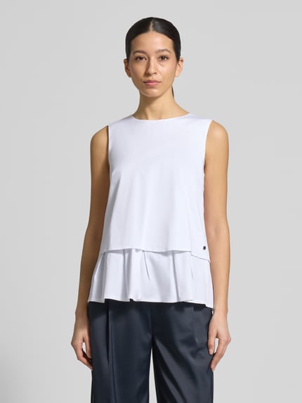 Frauenmodel trägt Blusenshirt mit Volantsaum und Rundhalsausschnitt von Marc Cain, weiß, gerader Schnitt, Baumwoll-Mix, Ganzkörperansicht von vorne.