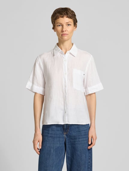 Vrouwenmodel draagt Loose Fit linnen blouse met borstzak van Tommy Hilfiger, effen kleuren look, korte mouw, knoopsluiting, materiaal: linnen, gestikt logo, achterpas met plooien, voorkant, Ganzkörperansicht von voren.