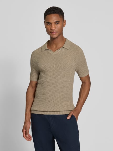 Męski model nosi Slim Fit Strick-Poloshirt mit Strukturmuster od bugatti, bawełniany miks, krój slim fit, beżowa tekstura, długość tyłu 68 cm, zdjęcie całej sylwetki z przodu