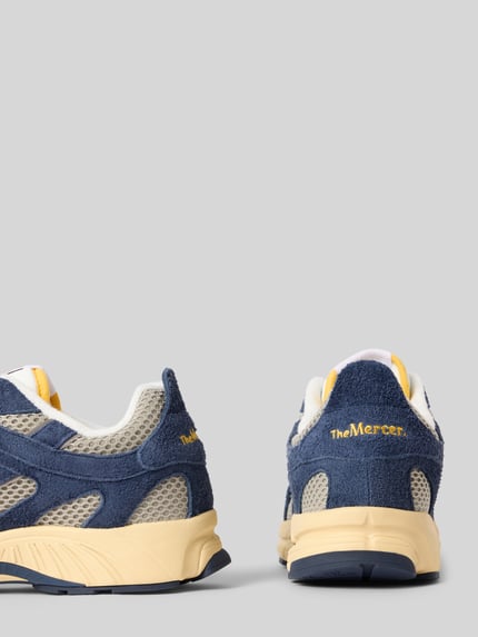 Productfoto, Sneaker uit ledermix model 'Re-Run Americana' van The Mercer, afgeronde pasvorm, gestructureerde zool, mesh en suède inzetstukken, label-detail, vetersluiting, kleur blauw-beige, context: herensneaker met hakhoogte 4 cm, schachthoogte 8 cm, schachtwijdte 8 cm.