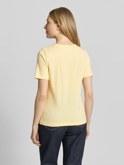 Vrouwenmodel draagt T-shirt met ronde hals van Christian Berg Woman in lichtgeel, puur katoen, regular fit, 1/2-mouwen, ruglengte bij maat S 60 cm. Ganzkörperansicht Rückansicht.