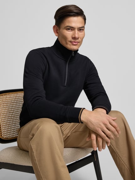 Męski model nosi Regular Fit troyer mit elastischen wykończeniami od Christian Berg Men, mieszanka bawełny, kołnierz zapinany, czarny, dł. tyłu 68 cm, dł. rękawa 66 cm, zbliżenie na górną część ciała z przodu.