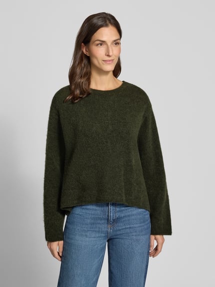 Vrouwenmodel draagt gebreide pullover van American Vintage, relaxed fit, Model 'VITOW', ronde hals, Ruglengte maat S 56 cm, Mouwlengte maat S 57 cm, donkergroene kleur, zachte textuur, Ganzkörperansicht van voren.