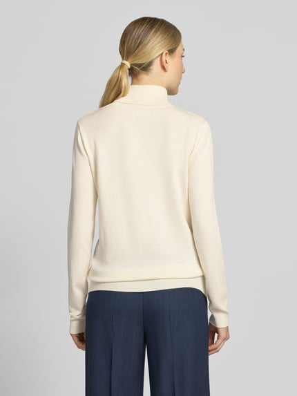 Frauenmodel trägt kremowy sweter z dzianiny z mieszanki wiskozy, krój slim fit, Golf, elastyczne wykończenia, Model 'IHLULS' od ICHI, długość tyłu w rozmiarze S: 61 cm, długość rękawów w rozmiarze S: 66 cm, widok całej sylwetki z tyłu