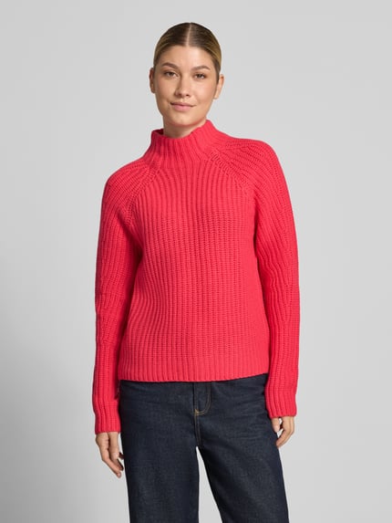 Frauenmodel trägt pinken Strickpullover aus Kaschmir-Baumwoll-Mix Modell 'LONA' von 0039 Italy, Struktur in Rippenoptik, Ganzkörperansicht von vorne. Rückenlänge 60 cm, Ärmellänge 78 cm, Regular Fit, Stehkragen.