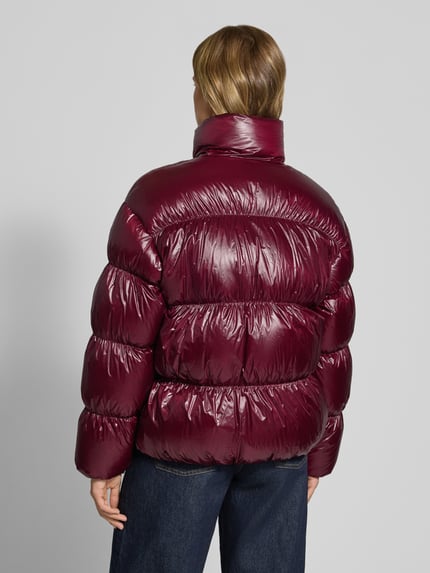Frauenmodel trägt Regular Fit Steppjacke mit Label Stitching von Tommy Jeans, unifarben, glänzend, Rückansicht, Ganzkörperansicht.