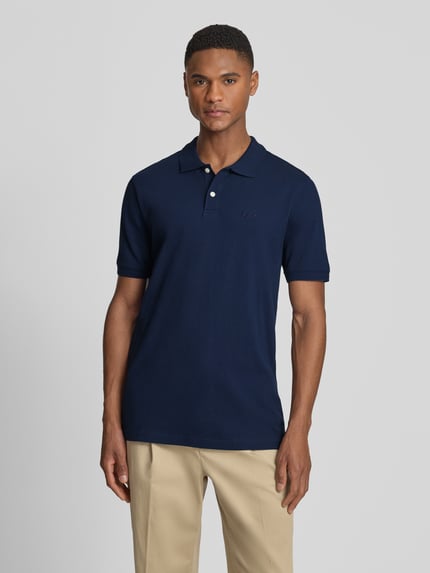 Męski model nosi Slim Fit Poloshirt mit Label-Stitching od GAP, granat, mieszanka bawełny i elastanu, krój slim fit, listwa guzikowa, długość tyłu w rozmiarze M: 70 cm, widok całej sylwetki z przodu.