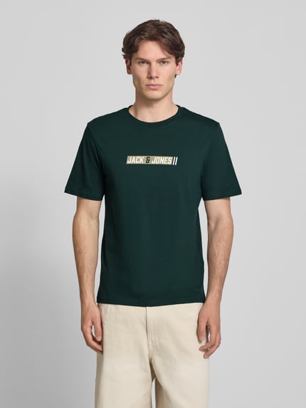 Männermodel trägt Regular Fit T-Shirt mit Logo-Print Modell 'Munk' von JACK & JONES, Herren T-Shirt aus Reine Baumwolle, Ganzkörperansicht von vorne. Rückenlänge bei Größe M: 74 cm.