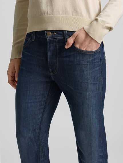Męski model nosi Straight Fit Jeans im 5-Pocket-Design Modell 'DAREN' od Lee, bawełniany miks ze stretchem, krój prosty, zapięcie na guzik i zamek, szerokość w rozmiarze 32/32: 42 cm, długość wewnętrzna nogawki: 79 cm, ciemnoniebieski denim, widoczne szwy, tekstura materiału, zbliżenie na górną część spodni, detal.