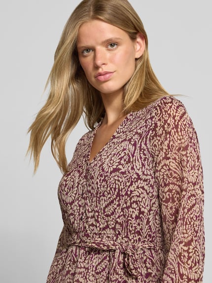 Frauenmodel trägt Tailliertes Blusenkleid mit Allover-Muster Modell 'CERA' von ONLY, weinrot-beige Muster, Damen Blusenkleid, Nahaufnahme Oberkörper.