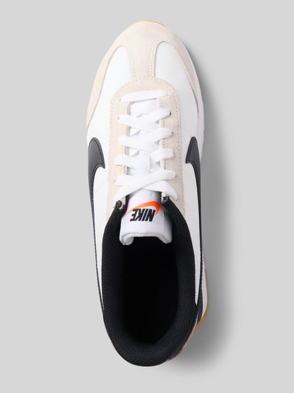 Produktfoto, Sneaker mit Label-Applikation Modell 'Pacific' von Nike in Weiß mit schwarzem Logo, abgerundete Form, Schnürverschluss, strukturierte Sohle, Absatzhöhe 2 cm, Schafthöhe 8 cm, Schaftweite 9 cm.