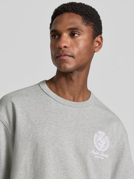 Männermodel trägt Relaxed Fit T-Shirt aus reiner Baumwolle von Polo Ralph Lauren, graue Farbe, weiche Textur, Nahaufnahme Oberkörper. Herren T-Shirt.