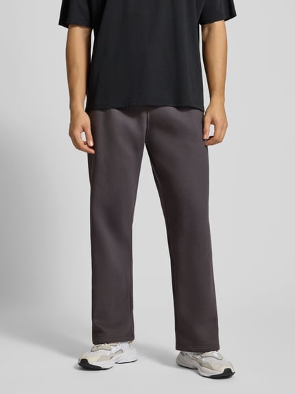 Männermodel trägt Sweatpants mit elastischem Bund von adidas Originals aus Baumwoll-Mix, lockerem Schnitt, Label-Stitching, Ganzkörperansicht von vorne.