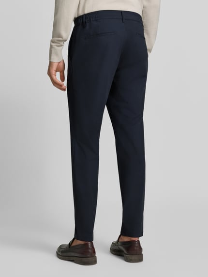 Männermodel trägt dunkelblaue Tapered Fit Stoffhose mit Viskose-Anteil Modell 'Phil' von Brax, glatte Oberfläche, Ganzkörperansicht Rückansicht, Herren Gerade Hose von Brax.