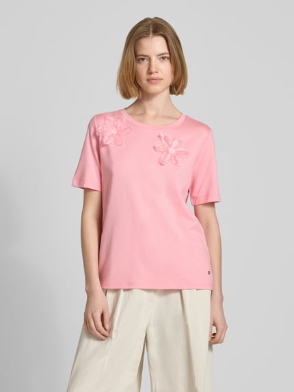 Modelka kobieca nosi Regular Fit T-Shirt mit floralem Zierbesatz od monari, mieszanka bawełny i modalu, dekolt okrągły, długość pleców w rozmiarze 36: 59 cm, jasnoróżowy kolor, struktura gładka z kwiatową aplikacją, widok całej sylwetki z przodu.