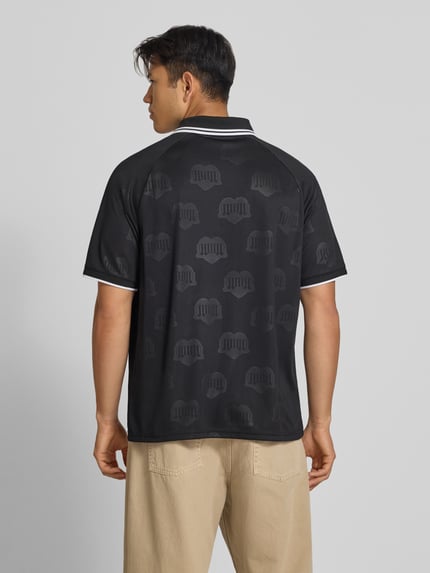 Männermodel trägt schwarzes Funktionsshirt mit dezentem Logo-Muster und weißem Kragen von Adidas, Modell 'Terrace', Ganzkörperansicht Rückansicht, Herren Funktionsshirt Regular Fit, Rückenlänge bei Größe M 71 cm.
