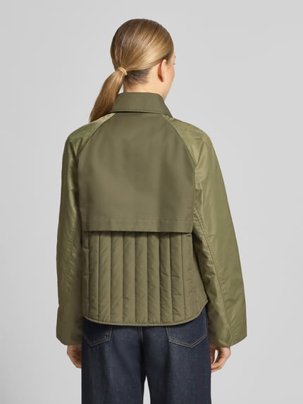Männermodel trägt Trenchcoat mit Eingrifftaschen Modell 'Zyla Neola' von MOS MOSH, kolor oliwkowy, bawełna, krój regular fit, widok całej sylwetki z tyłu