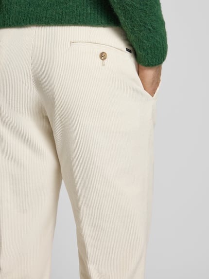 Männermodel trägt Stoffhose mit Gesäßtaschen Modell 'PARMA' von Hiltl aus cremefarbenem Cord, französische Eingrifftaschen, Nahaufnahme Hüfte.