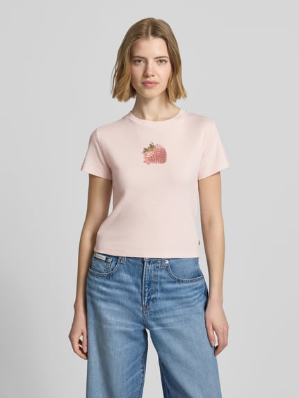 Frauenmodel trägt Regular Fit T-Shirt aus reiner Baumwolle von Levi's® in zartrosa mit Erdbeerprint, unifarben, Rundhals, Kurzarm, Ganzkörperansicht von vorne.