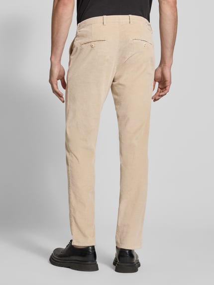 Männermodel trägt beigefarbene Modern Fit Cordhose aus Baumwoll-Mix Modell 'Fabio' von Brax, strukturierte Oberfläche, Ganzkörperansicht Rückansicht.
