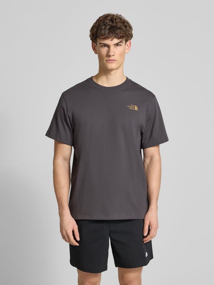 Männermodel trägt Relaxed Fit T-Shirt aus reiner Baumwolle von The North Face in anthrazit mit Rundhalsausschnitt und Label-Print, ganzkörperansicht von vorne.