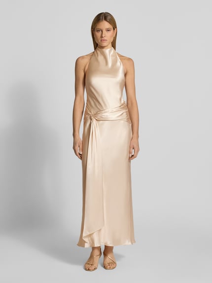 Frauenmodel trägt Abendkleid mit Neckholder Modell 'Abby' von Forever New aus champagnerfarbenem Satin, körpernaher Schnitt, Maxikleid, Ganzkörperansicht von vorne.