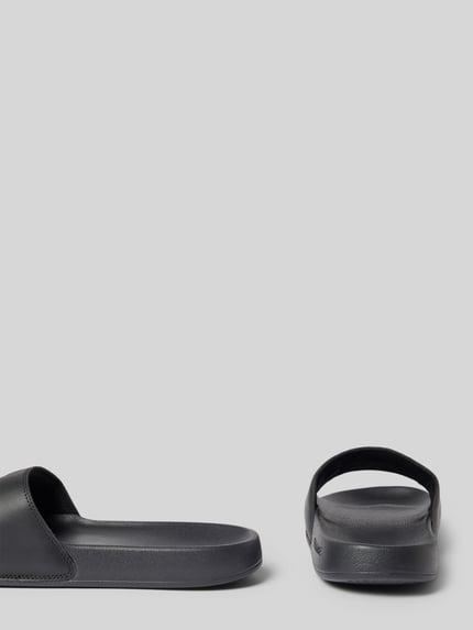 Produktfoto, Badeschuhe mit Logo Print Modell 'SERVE SLIDE' von Lacoste, czarne, jednokolorowe, zaokrąglony nosek, płaski obcas, strukturalna podeszwa, męskie
