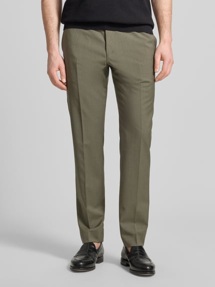 Männermodel trägt Straight Fit Stoffhose aus reiner Wolle Modell 'Tentua' von Tiger Of Sweden in Oliv, mit Gesäßtaschen, Haken- und Reißverschluss, Ganzkörperansicht von vorne. Bundweite 45 cm, Innenbeinlänge 80 cm bei Größe 50.