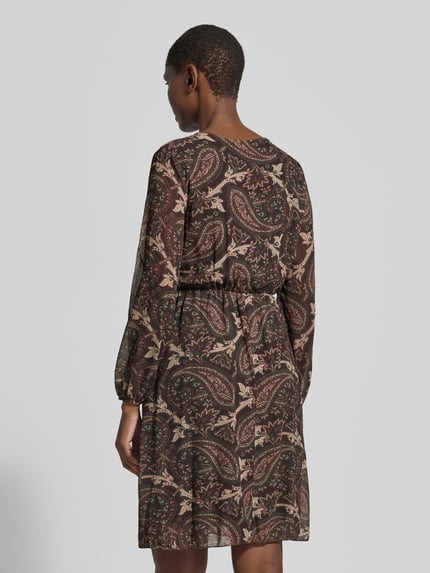 Frauenmodel trägt knielanges Kleid mit V-Ausschnitt Modell 'Th44ea' von ZABAIONE, Chiffon, A-Linie, Allover-Look, Ganzkörperansicht Rückansicht.