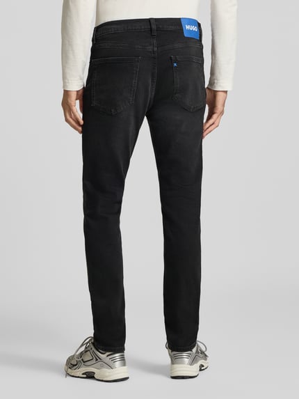 Männermodel trägt schwarze Super Slim Fit Jeans aus Baumwoll-Mix Modell 'Zane' von HUGO, Herren Slim Fit Jeans, Ganzkörperansicht Rückansicht.