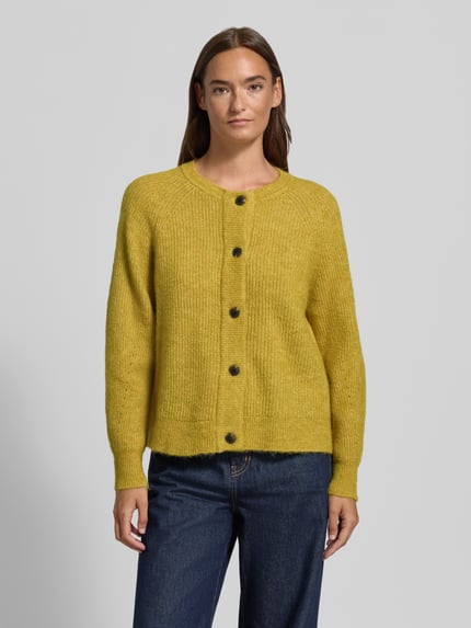 Frauenmodel trägt Relaxed Fit Strickjacke aus Woll-Mix Modell 'LULU' von Selected in Senfgelb, grobe Strickstruktur, Damen Strickjacke, Ganzkörperansicht von vorne.