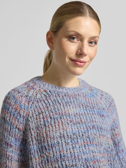 Frauenmodel trägt Strickpullover mit Rundhalsausschnitt von Smith and Soul, Grobstrick in Blau und Orange, Material-Mix mit Mohair-Anteil, Nahaufnahme Oberkörper.