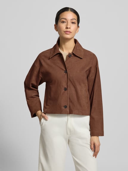 Modelka kobieca nosi Regular Fit Jacke aus echtem Lammvelours mit Umlegekragen od Windsor, brązowy kolor, z guzikami i kieszeniami, krój regular fit, widok całej sylwetki z przodu.
