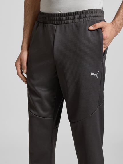 Männermodel trägt Sweatpants mit elastischem Bund von PUMA PERFORMANCE, Label-Print, französische Eingrifftaschen, Nahaufnahme Oberkörper.