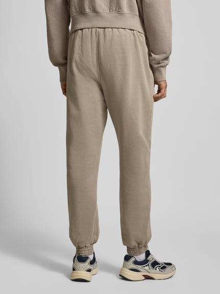 Männermodel trägt Sweatpants mit elastischem Bund von Pegador aus Baumwoll-Mix, lockerem Schnitt, Label-Stitching, Eingrifftaschen, Ganzkörperansicht Rückansicht.