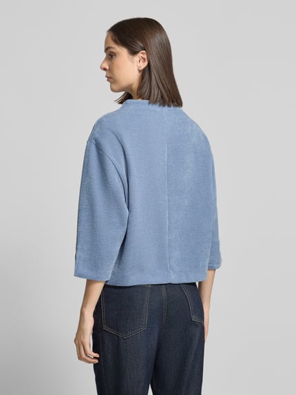 Frauenmodel trägt Relaxed Fit Strickpullover mit Stehkragen von ZABAIONE in Hellblau, 3/4-Arm, Strick-Optik, Ganzkörperansicht Rückansicht.