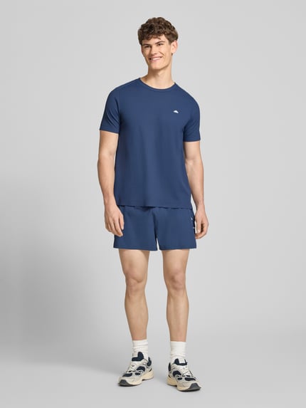 Männermodel trägt Shorts mit elastischem Bund Modell 'ERUDITO' von Ellesse, blauer Material-Mix mit Stretch-Anteil, Regular-Fit, Ganzkörperansicht von vorne.