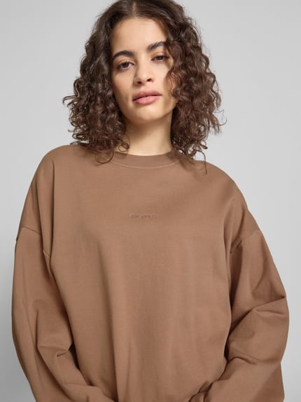 Kobiece model prezentuje Regular Fit Sweater mit Logo-Stitching Modell 'Croissant' von OH APRIL z bawełny, okrągły dekolt, elastyczne wykończenia, krój regular fit, damski sweter, wyhaftowane logo, ujęcie: zbliżenie na górną część ciała